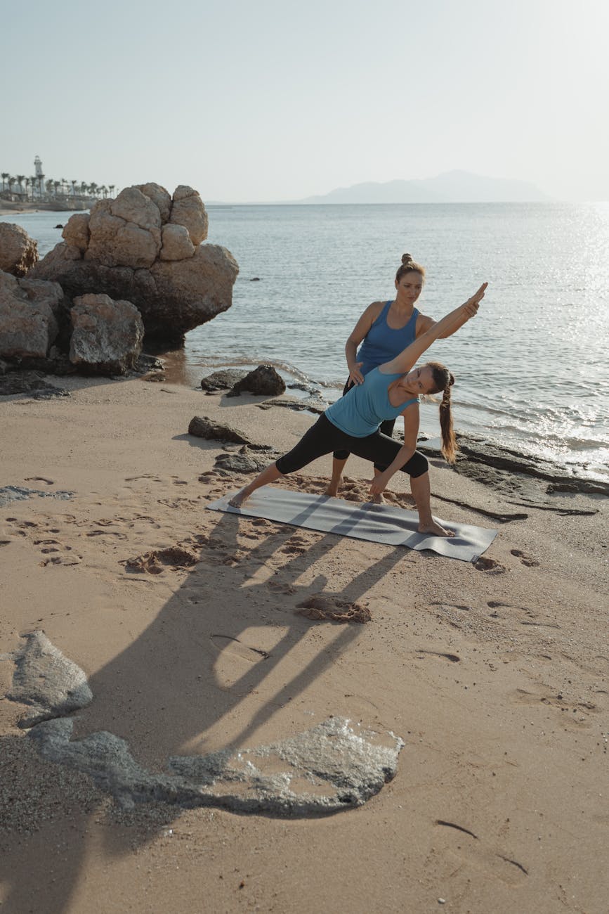 Woman doing a yoga pose on a beach at sunset with a calm ocean in the background